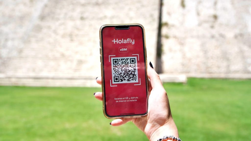 Asmuo, laikantis telefoną su įdiegta holafly